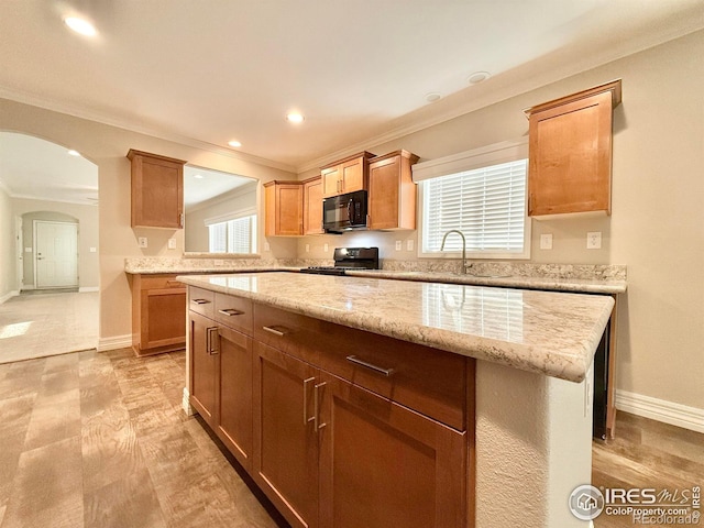 kitchen featuring arched walkways, a sink, black appliances, and ornamental molding