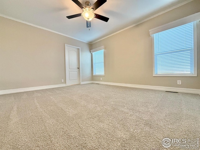 empty room with carpet, a ceiling fan, visible vents, ornamental molding, and baseboards