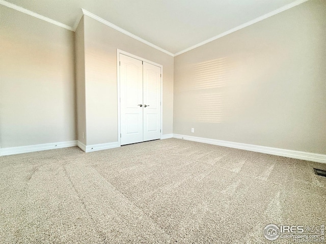 unfurnished bedroom featuring a closet, carpet flooring, baseboards, and crown molding