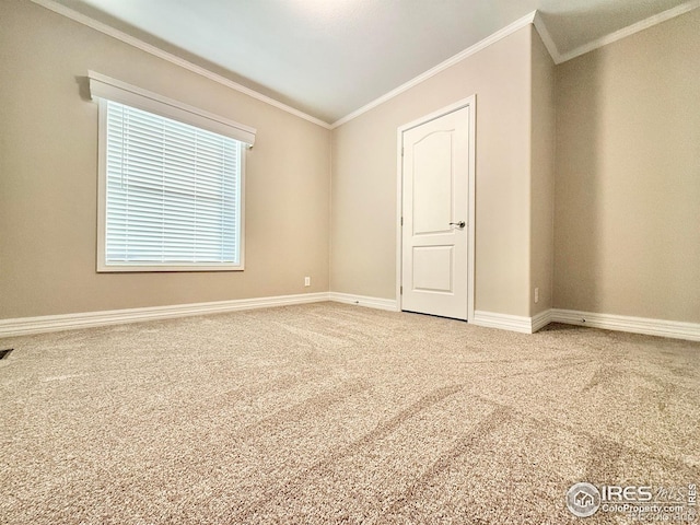 carpeted spare room featuring crown molding, visible vents, and baseboards