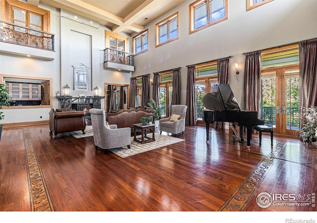 living room featuring wood-type flooring, beamed ceiling, a high ceiling, and coffered ceiling