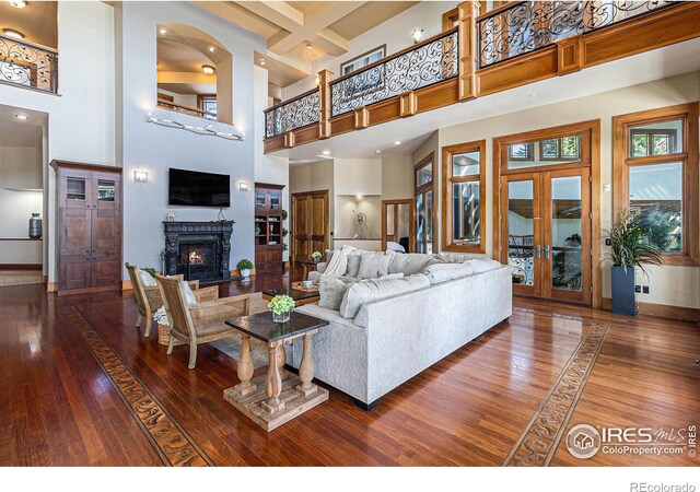 8532 Strawberry Ln, Niwot, CO 80503 - living room with french doors, baseboards, a high ceiling, a warm lit fireplace, and hardwood / wood-style flooring
