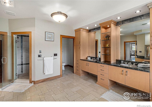 bathroom with walk in shower, vanity, and toilet