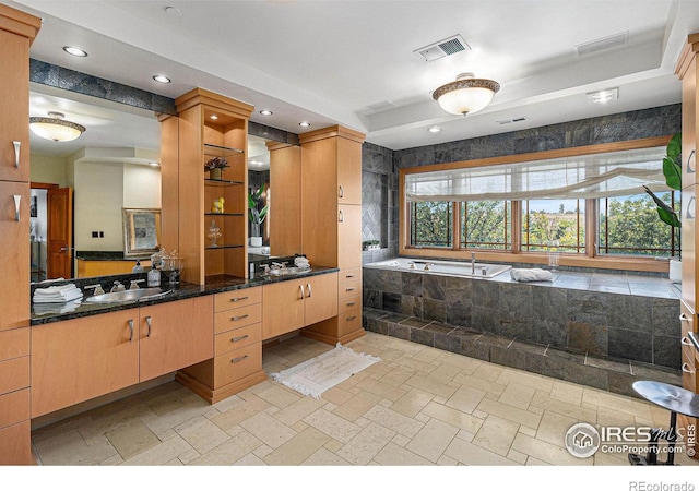 bathroom with tiled tub and vanity