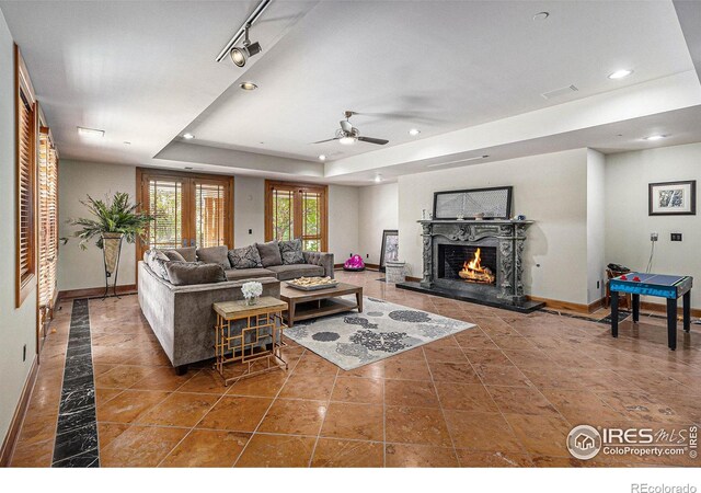 8532 Strawberry Ln, Niwot, CO 80503 - living area featuring recessed lighting, a warm lit fireplace, a raised ceiling, a ceiling fan, and baseboards