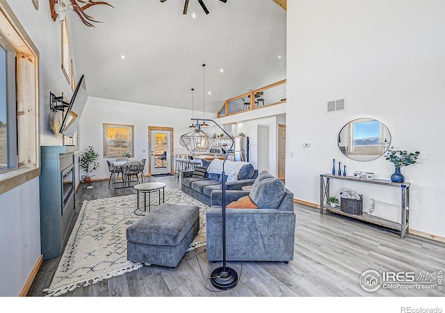 living room with a high ceiling, ceiling fan, and hardwood / wood-style flooring