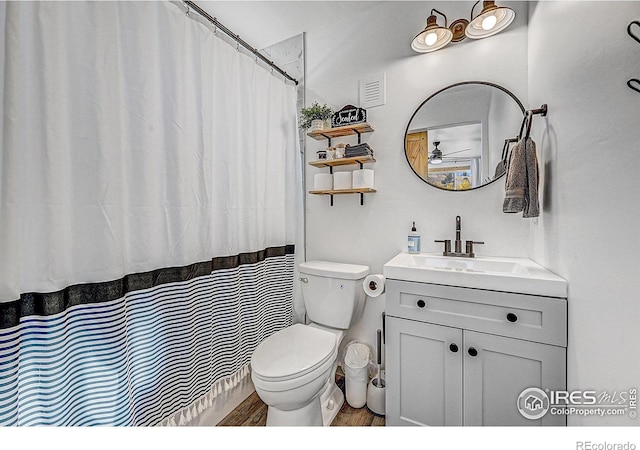 bathroom with curtained shower, hardwood / wood-style floors, vanity, and toilet