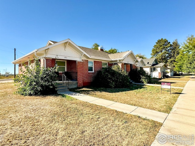 101-105 Factory St, Sterling, CO 80751 - view of front of property with brick siding, a front yard, and a chimney