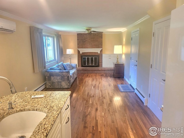 unfurnished living room featuring dark wood-type flooring, a baseboard heating unit, a brick fireplace, and a wall unit AC