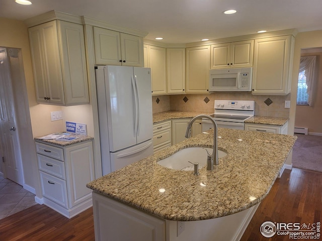 kitchen featuring an island with sink, light stone countertops, dark wood-type flooring, sink, and white appliances