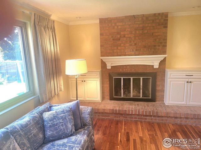 living room featuring a wealth of natural light, crown molding, a fireplace, and wood-type flooring