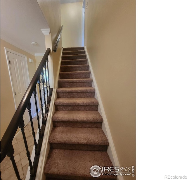 stairs featuring crown molding and tile patterned flooring