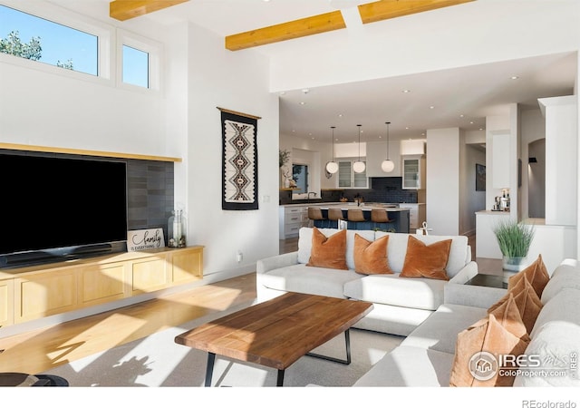 living room featuring beamed ceiling and light hardwood / wood-style flooring