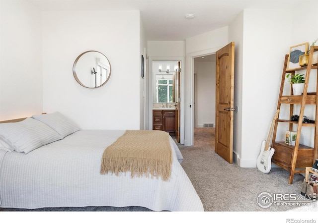 bedroom with connected bathroom, sink, and light carpet