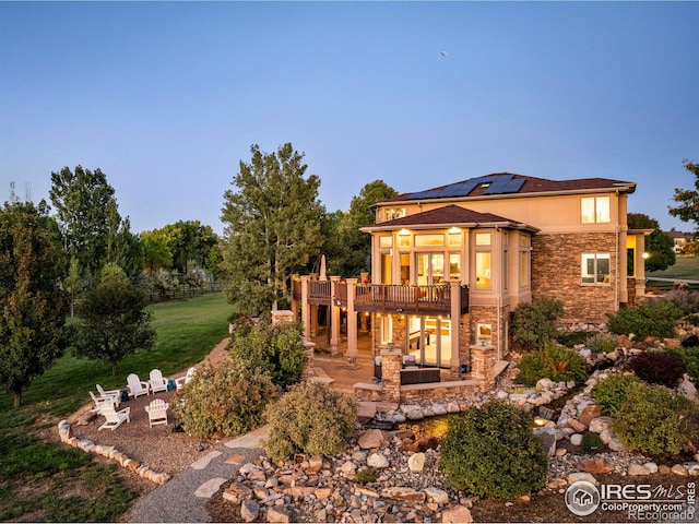 rear view of property featuring a wooden deck, a patio, and a fire pit