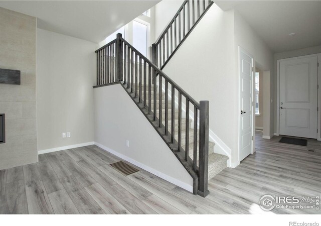 staircase featuring hardwood / wood-style flooring and a tile fireplace