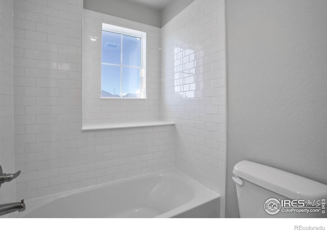 bathroom with tiled shower / bath combo and toilet