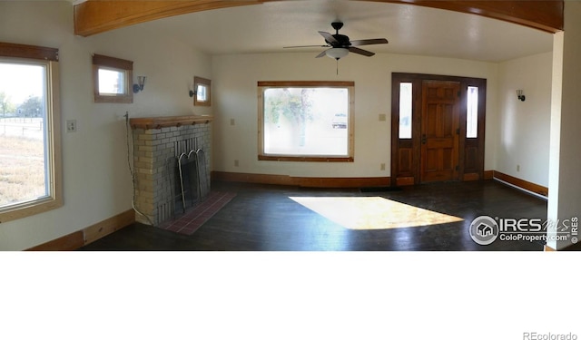 foyer entrance featuring dark hardwood / wood-style flooring, ceiling fan, a fireplace, and beamed ceiling