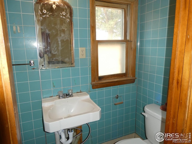 bathroom featuring sink, toilet, and tile walls