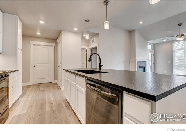 265 High Point Dr Unit 203, Longmont, CO 80504 - kitchen with dishwasher, a sink, dark countertops, light wood-style flooring, and white cabinets