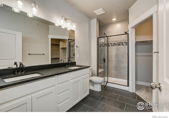 265 High Point Dr Unit 203, Longmont, CO 80504 - bathroom featuring a walk in closet, a shower stall, double vanity, toilet, and tile patterned floors