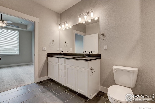 265 High Point Dr Unit 203, Longmont, CO 80504 - bathroom featuring double vanity, toilet, baseboards, ceiling fan, and a textured wall