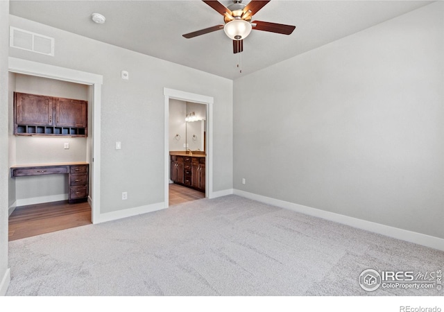 unfurnished bedroom featuring ensuite bath, ceiling fan, and light colored carpet