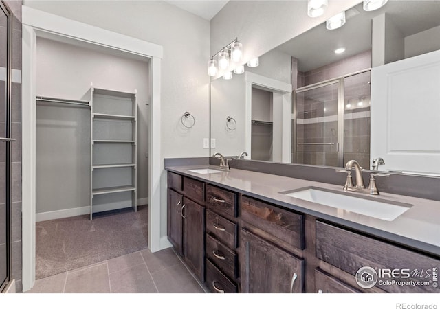 bathroom with tile patterned floors, a shower with shower door, and vanity