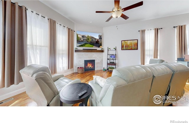 living room with ceiling fan, a fireplace, wood finished floors, and visible vents