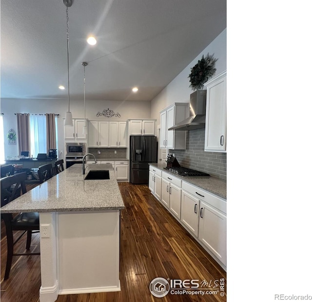 kitchen with dark wood-type flooring, a sink, white cabinets, appliances with stainless steel finishes, and wall chimney exhaust hood