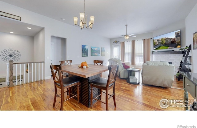 dining space featuring a chandelier, light wood finished floors, a fireplace, and recessed lighting