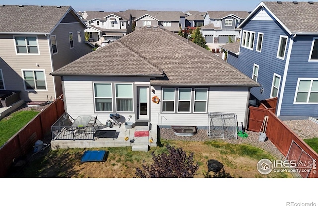 view of front facade featuring roof with shingles, a fenced backyard, and a residential view