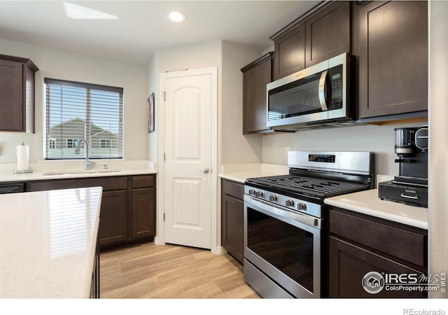 kitchen featuring dark brown cabinets, light hardwood / wood-style floors, appliances with stainless steel finishes, and sink