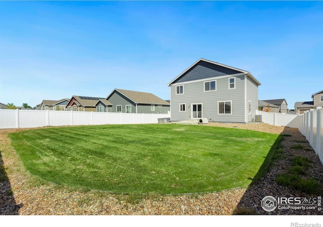 back of house featuring central air condition unit and a yard