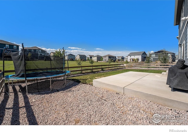 view of yard with a trampoline and a patio area