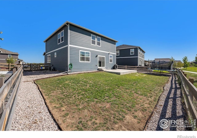 rear view of property featuring a trampoline, a lawn, a patio, and central AC unit