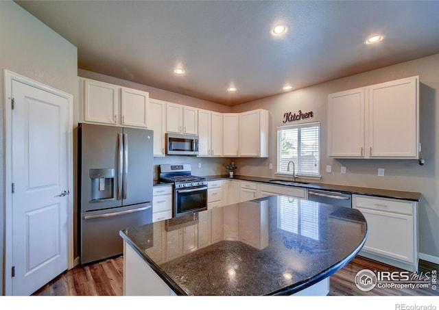 kitchen featuring sink, white cabinetry, appliances with stainless steel finishes, dark hardwood / wood-style floors, and dark stone counters