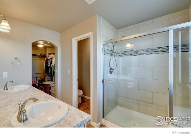 bathroom featuring a shower with door, toilet, vanity, and hardwood / wood-style flooring