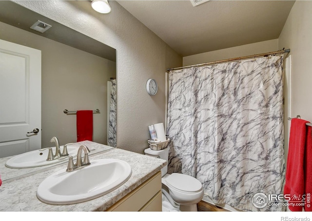 bathroom with a shower with curtain, vanity, toilet, and a textured ceiling