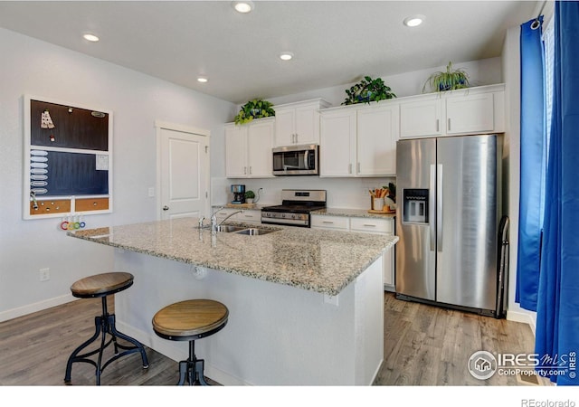 kitchen with white cabinets, stainless steel appliances, sink, and light stone countertops