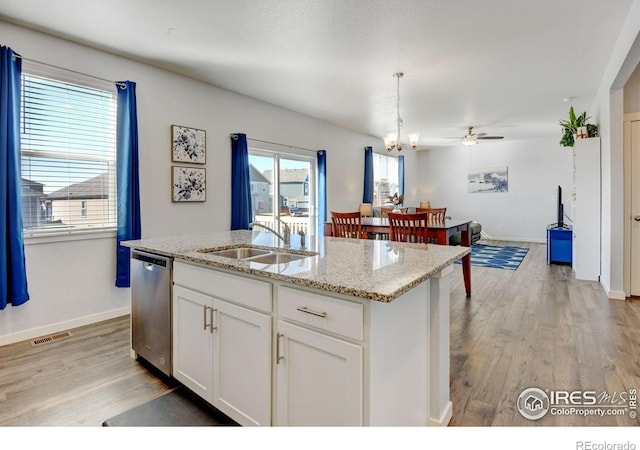 kitchen featuring an island with sink, white cabinets, pendant lighting, stainless steel dishwasher, and sink