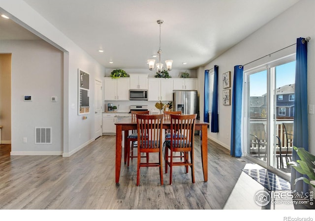 dining area with light hardwood / wood-style floors and a chandelier