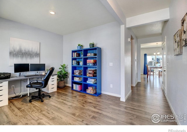 home office featuring wood-type flooring and a notable chandelier