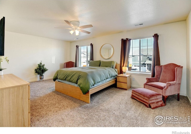 bedroom with light carpet, multiple windows, ceiling fan, and a textured ceiling