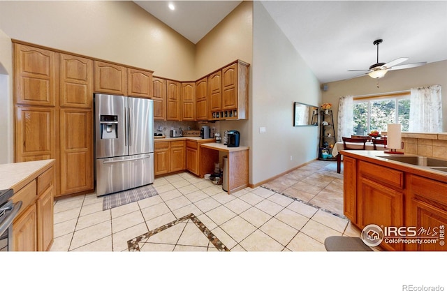 kitchen with stainless steel refrigerator with ice dispenser, tasteful backsplash, ceiling fan, high vaulted ceiling, and light tile patterned flooring