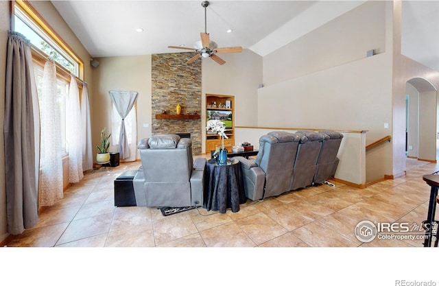 living room featuring a stone fireplace, ceiling fan, high vaulted ceiling, and light tile patterned flooring