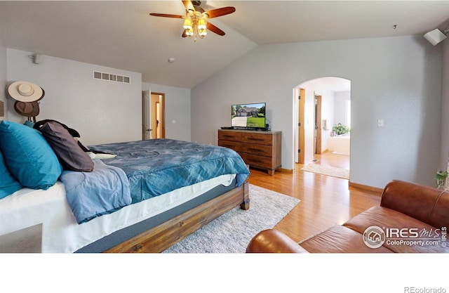 bedroom with ceiling fan, light hardwood / wood-style floors, lofted ceiling, and connected bathroom