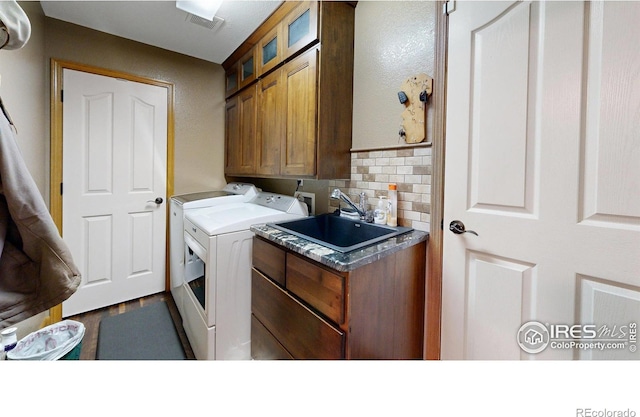 clothes washing area featuring cabinets, washing machine and dryer, and sink