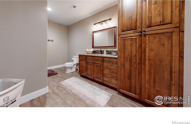 bathroom with hardwood / wood-style floors, vanity, and toilet