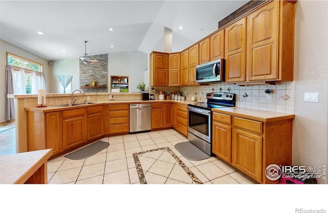 kitchen featuring sink, hanging light fixtures, stainless steel appliances, kitchen peninsula, and vaulted ceiling